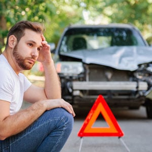 Man sitting by car accident scene symbolizing mistakes to avoid - Hobaica Law Office